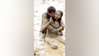 Couple canoodles in mud for 'post wedding' photo shoot