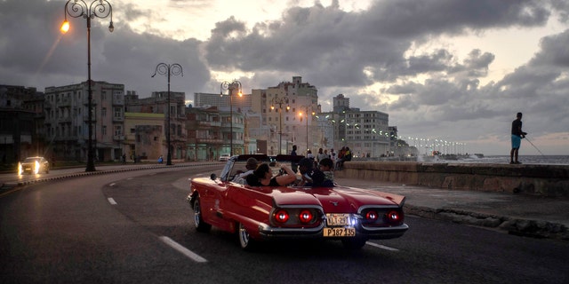 In this Nov. 10, 2019, photo, tourists take a joy ride along the malecon sea wall in Havana, Cuba. The city of Havana celebrated its 500th anniversary on Nov. 16. (AP Photo/Ramon Espinosa)