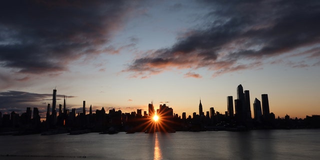 The sun rises down 42nd Street behind the skyline of midtown Manhattan and the Empire State Building in New York City on November 28, 2019 as seen from Weehawken, New Jersey.