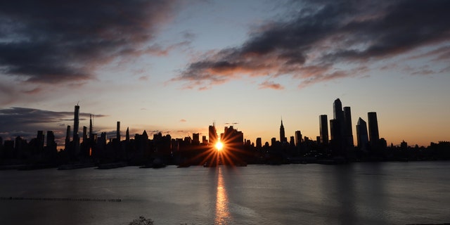 Le soleil se lève sur la 42e rue derrière l'horizon du centre-ville de Manhattan et de l'Empire State Building à New York le 28 novembre 2019, vu de Weehawken, New Jersey.