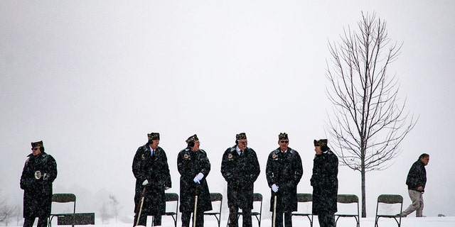 Members of the military stand on top of a hill preparing to fire their guns for the 21-gun salute during a Veterans Day ceremony at The Great Lakes Cemetery on Monday, Nov. 11, 2019.