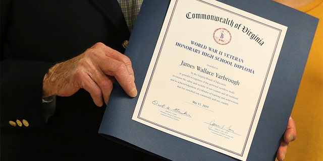 During a Veterans Day ceremony at Washington-Henry Elementary school in Mechanicsville, Va., WWII veteran James Wallace Yarbrough is presented an honorary diploma by the school. (Dean Hoffmeyer/Richmond Times-Dispatch via AP)
