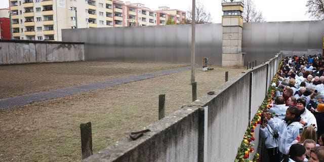 People stuck flowers in remains of the Berlin Wall during a commemoration ceremony to celebrate the 30th anniversary of the fall of the Berlin Wall at the Wall memorial site at Bernauer Strasse in Berlin, Saturday, Nov. 9, 2019.