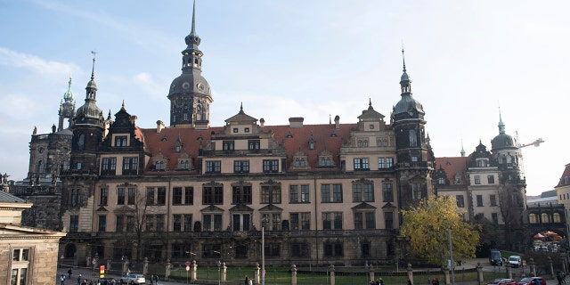 People stand in front of the Residenzschloss, Residence Palace, building with the Green Vault in Dresden, Monday, Nov. 25, 2019. Authorities in Germany say thieves have carried out a brazen heist at Dresden’s Green Vault, one of the world’s oldest museum containing priceless treasures from around the world. (Sebastian Kahnert/dpa via AP)