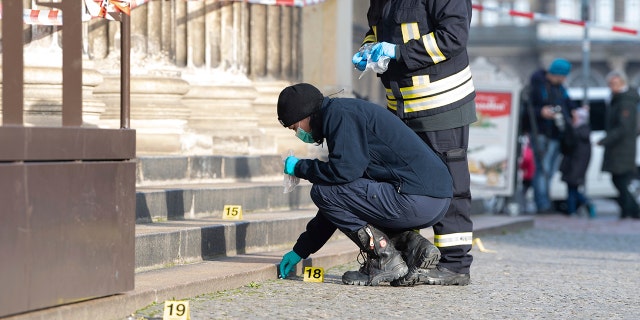 Police officers work behind caution tape at the Schinkelwache building in Dresden, Monday, Nov. 25, 2019. (Sebastian Kahnert/dpa via AP)