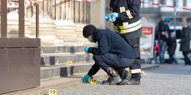 Police officers work behind caution tape at the Schinkelwache building in Dresden, Monday, Nov. 25, 2019.  (Sebastian Kahnert/dpa via AP)