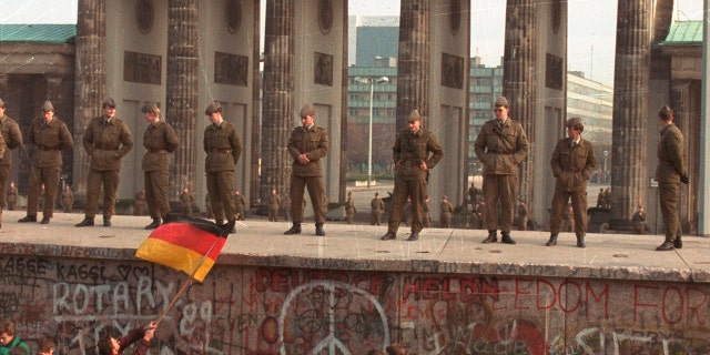 East German border guards standing on top of the Berlin wall in front of the Brandenburg Gate on Nov. 11, 1989. (AP Photo/Lionel Cironneau, File)