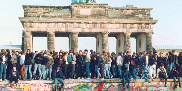 In this Friday, Nov. 10, 1989, file photo, hundreds of Berliners climb atop the Berlin Wall at Brandenburg Gate in Berlin, demanding in a peaceful protest that the wall will be pulled down. When the Berlin Wall fell, the Soviet Union stepped back, letting East Germany's communist government collapse and then quickly accepting German unification.