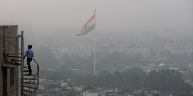 An Indian walks up to the stairs as Delhi's skyline is seen enveloped in smog and dust in New Delhi, India, Friday, Nov. 1, 2019. (AP Photo/Manish Swarup)