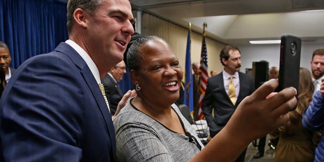 Oklahoma Gov. Kevin Stitt, left, poses for a selfie with Joy Block, right, of Tulsa, Okla., following a news conference Friday to announce that Oklahoma will release more than 400 inmates after the board approved what they say is the largest single-day mass commutation in U.S. history. (AP Photo/Sue Ogrocki)