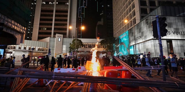 Demonstrators gather near a burning barricade in the street during a protest in Hong Kong, Saturday, Nov. 2, 2019. Anti-government protesters attacked the Hong Kong office of China's official Xinhua News Agency for the first time Saturday after chaos broke out downtown, with police and demonstrators trading gasoline bombs and tear gas as the protest movement approached the five-month mark. 