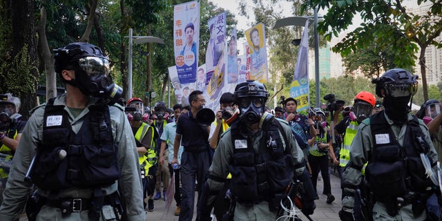 Police in riot gear gather near campaign banners in Hong Kong, Saturday, Nov. 2, 2019. Anti-government protesters attacked the Hong Kong office of China's official Xinhua News Agency for the first time Saturday after chaos broke out downtown, with police and demonstrators trading gasoline bombs and tear gas as the protest movement approached the five-month mark.