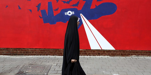 A woman walks past a new anti-U.S. mural on the wall of former U.S. embassy portraying the interception of Global Hawk US drone by Iran in Persian Gulf, after an unveiling ceremony in Tehran, Iran, Saturday, Nov. 2, 2019. (AP Photo/Vahid Salemi)