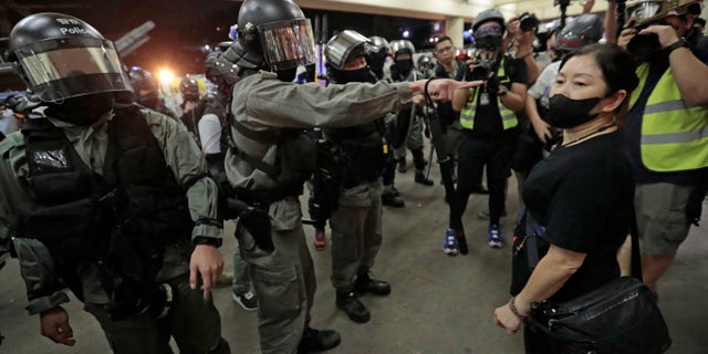 Police in riot gear ask a woman to take off her mask outside a train station in Hong Kong, Sunday, Nov. 3, 2019. Riot police stormed several malls in Hong Kong on Sunday in a move to thwart more pro-democracy protests, as the city's leader heads to Beijing for talks on deepening economic integration between the semi-autonomous Chinese territory and mainland China. (AP Photo/Dita Alangkara)