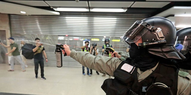 A riot police officer fires pepper spray toward people at a shopping mall in Hong Kong, Sunday, Nov. 3, 2019. Riot police stormed several malls in Hong Kong on Sunday in a move to thwart more pro-democracy protests, as the city's leader heads to Beijing for talks on deepening economic integration between the semi-autonomous Chinese territory and mainland China. (AP Photo/Dita Alangkara)