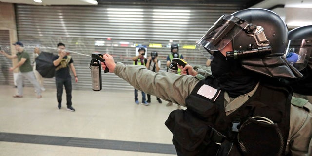 A riot police officer fires pepper spray toward people at a shopping mall in Hong Kong, Sunday, Nov. 3, 2019. Riot police stormed several malls in Hong Kong on Sunday in a move to thwart more pro-democracy protests, as the city's leader heads to Beijing for talks on deepening economic integration between the semi-autonomous Chinese territory and mainland China. (AP Photo/Dita Alangkara)
