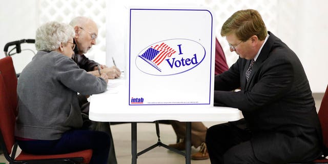 Republican nominee for governor and current Lt. Gov. Tate Reeves, right, joins other registered voters in voting at his Flowood, Miss., precinct, Tuesday Nov. 5, 2019. Voters are having their say in Mississippi's most hotly contested governor's race since 2003. They are also selecting six other statewide officials and deciding a host of legislative and local offices. (AP Photo/Rogelio V. Solis)