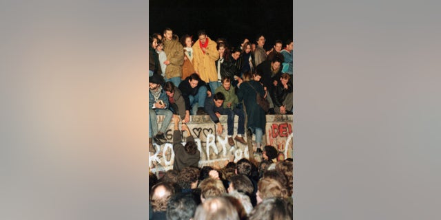 In this Saturday Nov. 11, 1989 file photo, hundreds of Berliners climb on top of the Berlin Wall at Brandenburg Gate in Berlin, demanding in a peaceful protest that the wall will be pulled down. 