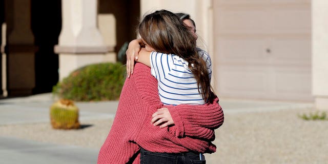 Madelyn Staddon, right, a relative of some of the members of a Mormon community who were attacked while traveling near the US-Mexico border, embraces a neighbor outside her home, Tuesday, Nov. 5, 2019, in Queen Creek, Ariz. Drug cartel gunmen ambushed three vehicles along a road near the state border of Chihuahua and Sonora on Monday, slaughtering at least six children and three women from the extended LeBaron family, all of them U.S. citizens living in northern Mexico, authorities said Tuesday. (AP Photo/Matt York)