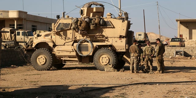 U.S. Army soldiers stand outside their armored vehicle on a joint base with Iraqi army south of Mosul, Iraq, Feb. 23, 2017.
