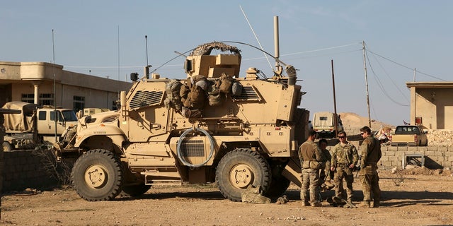 U.S. Army soldiers stand outside their armored vehicle on a joint base with Iraqi army south of Mosul, Iraq, Feb. 23, 2017.