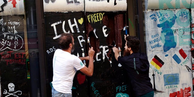 French chocolate maker Patrick Roger, left, and his creative assistant Angelo Dao, right, destroy a reproduction of the Berlin wall in chocolate, to mark the 30th anniversary of the fall of the Berlin Wall, in Paris, Saturday, Nov. 9, 2019. 