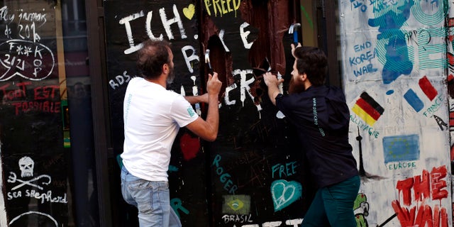 French chocolate maker Patrick Roger, left, and his creative assistant Angelo Dao, right, destroy a reproduction of the Berlin wall in chocolate, to mark the 30th anniversary of the fall of the Berlin Wall, in Paris, Saturday, Nov. 9, 2019.