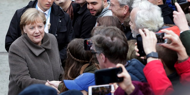 German Chancellor Angela Merkel, left, shakes hands with visitors prior to a memorial service in the chapel at the Berlin Wall Memorial in Berlin, Germany, Saturday, Nov. 9, 2019.