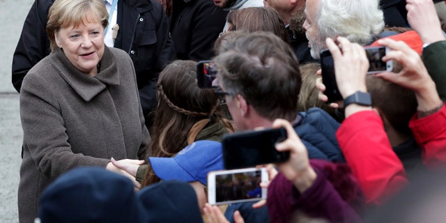 German Chancellor Angela Merkel, left, shakes hands with visitors prior to a memorial service in the chapel at the Berlin Wall Memorial in Berlin, Germany, Saturday, Nov. 9, 2019.