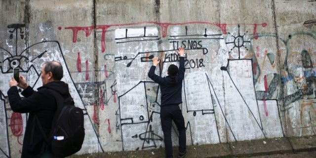 Tourist take photos at remains of the Berlin Wall after commemorations celebrating the 30th anniversary of the fall of the Berlin Wall at the Wall memorial site at Bernauer Strasse in Berlin, Saturday, Nov. 9, 2019.