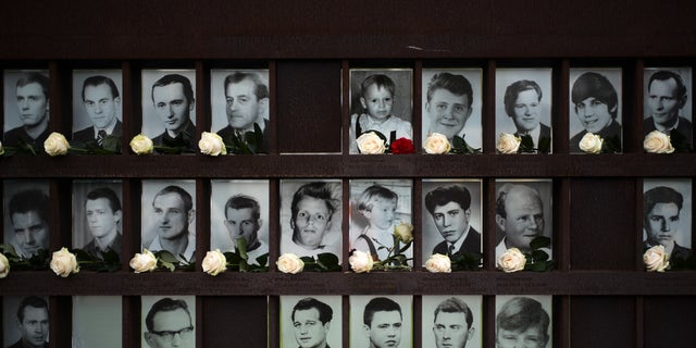 Flowers dropped in front of portraits from people died at the Berlin wall after commemorations celebrating the 30th anniversary of the fall of the Berlin Wall at the Wall memorial site at Bernauer Strasse in Berlin, Saturday, Nov. 9, 2019. 