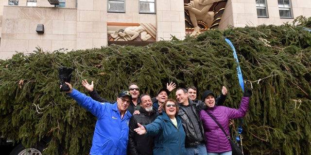 Carol Schultz, center, donor of this year's Rockefeller Center Christmas tree, poses with her family in front of her 77-foot tall Norway Spruce she donated to serve as the 2019 Rockefeller Center Christmas tree.