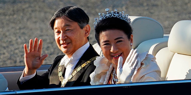 Japanese Emperor Naruhito, left, and Empress Masako, right, wave during the royal motorcade in Tokyo, Sunday, Nov. 10, 2019. (Associated Press)