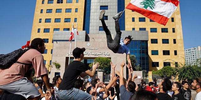A student protester is thrown into the air by his colleagues in front of the education ministry in Beirut on Tuesday. (AP Photo/Bilal Hussein)