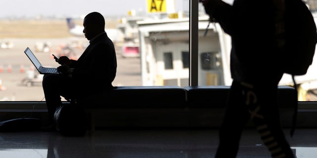 In this 2018 image, travelers check their phones at Indianapolis International Airport. (AP Photo/Michael Conroy)