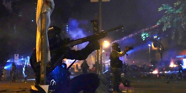 Police in riot gear prepare to fire as they move into the campus of Hong Kong Polytechnic University in Hong Kong.