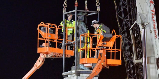 Workers prepare to remove a Confederate statue from its granite pedestal by the Chatham County courthouse in Pittsboro, N.C.