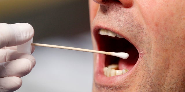 A police officer poses to illustrate a saliva test in Grevenbroich, Germany. (Roland Weihrauch/dpa via AP)