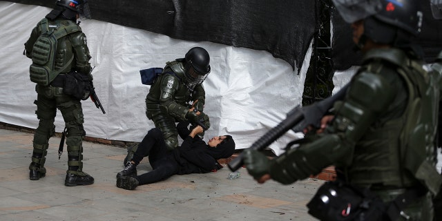 Riot police detain an anti-government protester in Bogota, Colombia, Saturday, Nov. 23, 2019. Authorities in Colombia are maintaining heightened police and military presence in the nation's capital following two days of unrest. (AP Photo/Ivan Valencia)