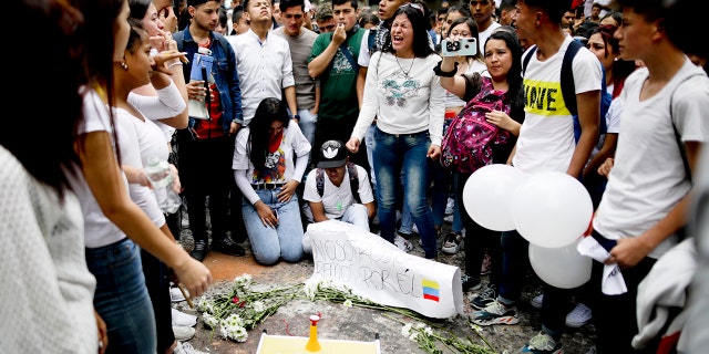 Youth attend a vigil for Dilan Cruz, who was injured during clashes between anti-government protesters and police, in Bogota, Colombia, Sunday, Nov. 24, 2019. President Ivan Duque said he was ordering an urgent investigation to determine who was responsible for the injuries of the 18-year-old student, who is in hospital in critical condition after he was hit in the head Saturday, apparently by a tear gas canister. (AP Photo/Ivan Valencia)