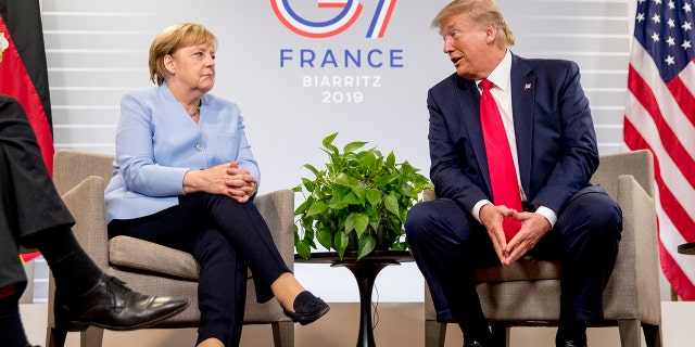 FILE - In this Monday, Aug. 26, 2019 file photo, U.S. President Donald Trump, accompanied by German Chancellor Angela Merkel, left, speaks during a bilateral meeting at the G-7 summit in Biarritz, France. A new study of the Pew Research Center and the Koerber-Stiftung foundation shows Germans and Americans continue to have notably different perspectives on the relationship between their two countries: Americans are much more optimistic about bilateral ties than Germans. (AP Photo/Andrew Harnik, File)