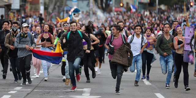Anti-government demonstrators run during a protest in Bogota, Colombia, Monday, Nov. 25, 2019. Authorities are maintaining a heightened police presence amidst scattered unrest in the aftermath of a mass protest that drew about 250,000 to the streets Thursday. (AP Photo/Fernando Vergara)