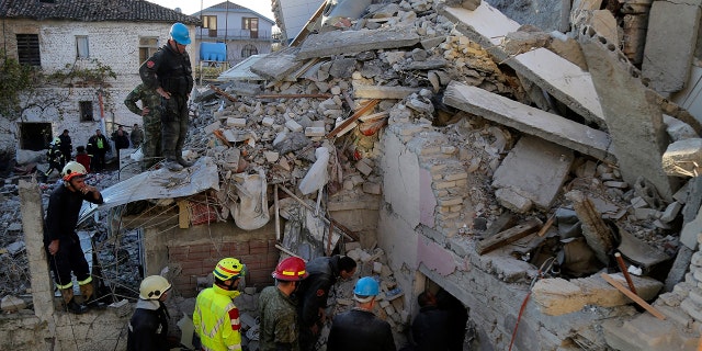 Rescuers try to free a man from a collapsed building after a magnitude 6.4 earthquake in Thumane, western Albania, Tuesday, Nov. 26, 2019. Rescue crews with excavators searched for survivors trapped in toppled apartment buildings and hotels Tuesday after a powerful pre-dawn earthquake in Albania killed at least 18 people and injured more than 600. (AP Photo/Visar Kryeziu)