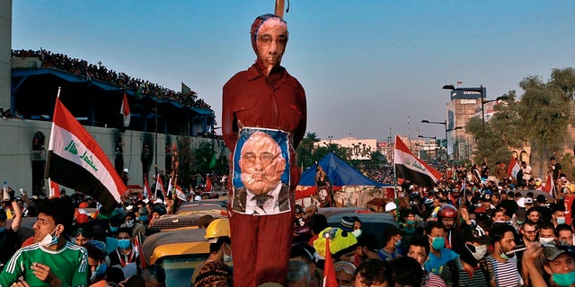 In this Wednesday, Oct. 30, 2019 file photo, anti-government protesters hold an effigy of Iraqi Prime Minister Adel Abdel-Mahdi during ongoing protests in Baghdad. Celebrations erupted in Iraq's Tahrir Square on Friday where anti-government protesters have been camped out for nearly two months following an announcement by Iraqi Prime Minister Adel Abdul-Mahdi, would be resigning. (AP Photo/Khalid Mohammed, File)