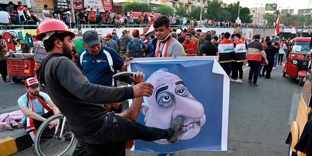 In this Sunday, Nov. 3, 2019 file photo, protesters hit a poster showing Iraqi Prime Minister Adel Abdel-Mahdi with shoes during ongoing anti-government protests in Baghdad. (AP Photo/Khalid Mohammed, File)