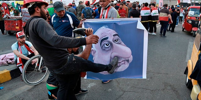 In this Sunday, Nov. 3, 2019 file photo, protesters hit a poster showing Iraqi Prime Minister Adel Abdel-Mahdi with shoes during ongoing anti-government protests in Baghdad. (AP Photo/Khalid Mohammed, File)