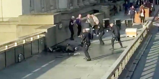 In a screenshot taken from video made available by @HLOBlog, a man is surrounded by police after an incident on London Bridge on Friday. (@HLOBlog via AP)