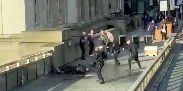 In a screenshot taken from video made available by @HLOBlog, a man is surrounded by police after an incident on London Bridge on Friday. (@HLOBlog via AP)