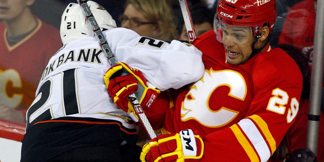 FILE - In this April 7, 2012, file photo, Anaheim Ducks' Sheldon Brookbank, left, checks Calgary Flames' Akim Aliu, a Nigerian-born Canadian, during third period NHL hockey action in Calgary, Alberta. (AP Photo/The Canadian Press, Jeff McIntosh, File)