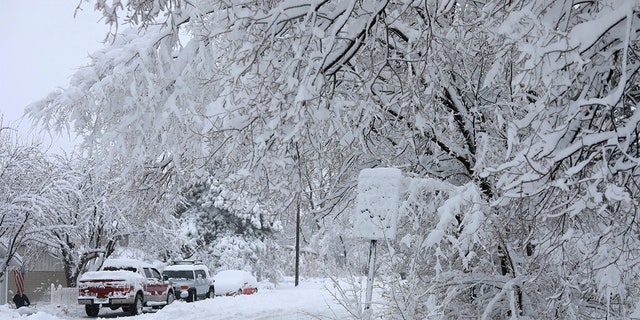 Street signs are covered in snow in north Flagstaff, Ariz., Friday, Nov. 29, 2019. A powerful storm making its way east from California is threatening major disruptions during the year's busiest travel weekend, as forecasters warned that intensifying snow and ice could thwart millions across the country hoping to get home after Thanksgiving.